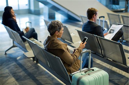 simsearch:6109-08929459,k - Commuter with coffee cup using mobile phone in waiting area at airport Foto de stock - Royalty Free Premium, Número: 6109-08929537