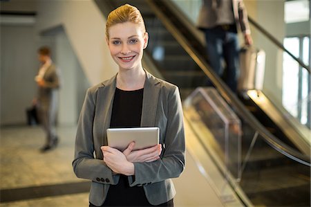 simsearch:6109-08929459,k - Portrait of businesswoman holding digital tablet at airport Foto de stock - Royalty Free Premium, Número: 6109-08929606