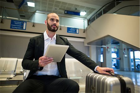 Businessman using digital tablet at airport Stock Photo - Premium Royalty-Free, Code: 6109-08929621