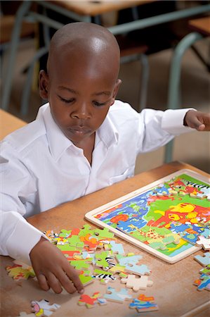 school and uniform and african - Young African schoolboy playing with a puzzle in a classroom Stock Photo - Premium Royalty-Free, Code: 6110-06702597