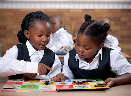 simsearch:6110-06702680,k - Young African schoolgirls looking through a picture book in class Foto de stock - Sin royalties Premium, Código: 6110-06702599