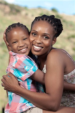 simsearch:6110-06702656,k - Young African girl and her mother sitting on a rock, looking at camera Foto de stock - Royalty Free Premium, Número: 6110-06702647