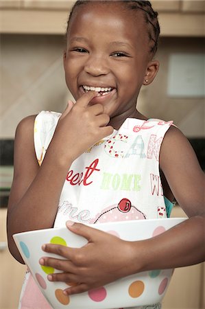 simsearch:6110-06702795,k - Young African child licks dough off of her finger while smiling Foto de stock - Royalty Free Premium, Número: 6110-06702661