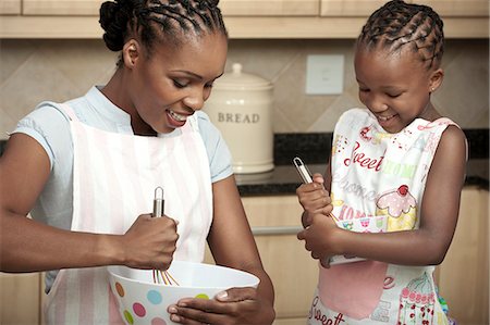 simsearch:6110-06702795,k - Young African child baking with her mother, smiling Foto de stock - Royalty Free Premium, Número: 6110-06702667
