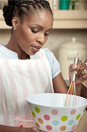 simsearch:6110-06702760,k - African woman whisking in a kitchen Fotografie stock - Premium Royalty-Free, Codice: 6110-06702668
