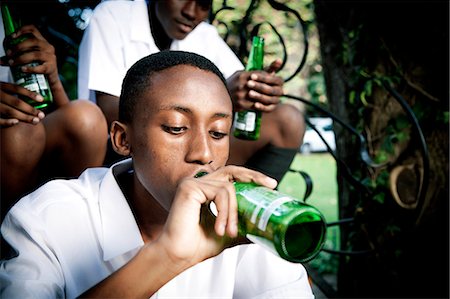 simsearch:6110-06702683,k - An African teenage boy sitting with his friends, drinking alcohol Stock Photo - Premium Royalty-Free, Code: 6110-06702682