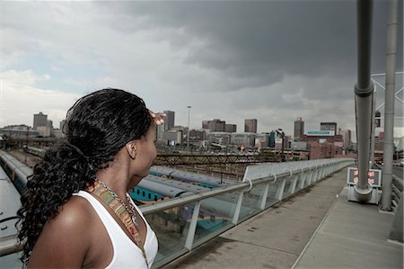 Young African female standing with a Johannesburg city scene in the background Foto de stock - Sin royalties Premium, Código: 6110-06702607
