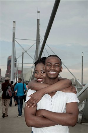 Young African couple standing together with a Johannesburg city scene in the background Stock Photo - Premium Royalty-Free, Code: 6110-06702608