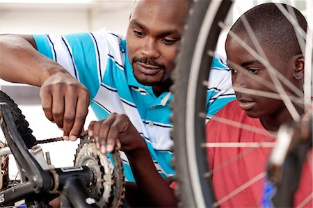 simsearch:6110-06702795,k - African Father and son working on a bicycle Foto de stock - Royalty Free Premium, Número: 6110-06702613