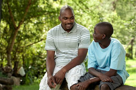 simsearch:6110-06702795,k - African father and son sitting outside in a garden Foto de stock - Royalty Free Premium, Número: 6110-06702627