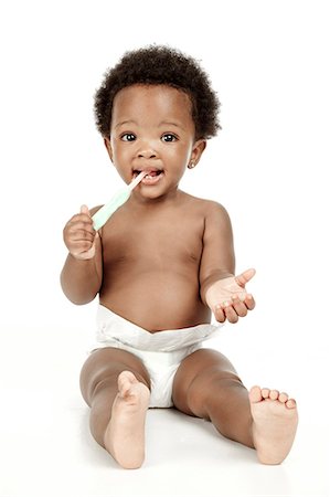 An infant sitting in front of a white background, smiling Stock Photo - Premium Royalty-Free, Code: 6110-06702748