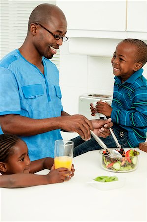 simsearch:6110-06702748,k - Young African father making food in the kitchen with his children Foto de stock - Royalty Free Premium, Número: 6110-06702773