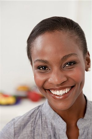 simsearch:6110-06702748,k - Young African woman standing in a kitchen smiles at camera Foto de stock - Royalty Free Premium, Número: 6110-06702770