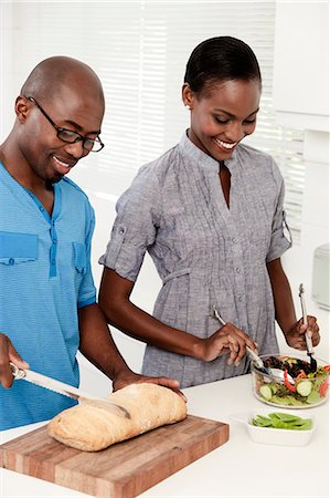 simsearch:6110-06702748,k - Young African married couple making food together in the kitchen Foto de stock - Royalty Free Premium, Número: 6110-06702774