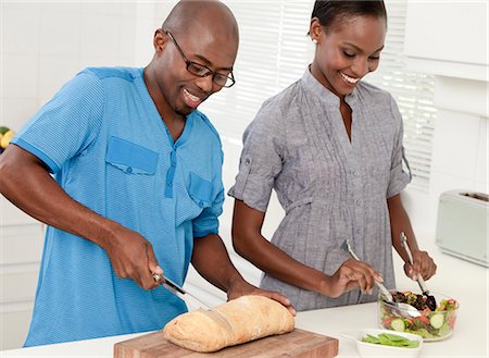 simsearch:6110-06702795,k - Young African married couple making food together in the kitchen Foto de stock - Royalty Free Premium, Número: 6110-06702775
