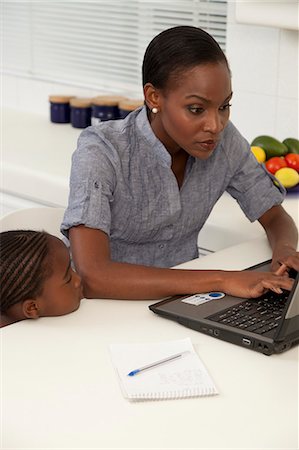 simsearch:6110-06702748,k - Young African mother trying to work on her laptop while her children play in the background Foto de stock - Royalty Free Premium, Número: 6110-06702786