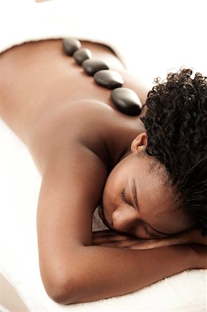 simsearch:6110-06702760,k - Young black woman receiving a hot stone massage Fotografie stock - Premium Royalty-Free, Codice: 6110-06702712