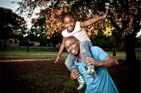 simsearch:6110-06702748,k - Young African Father playing in a park with his daughter Foto de stock - Royalty Free Premium, Número: 6110-06702802