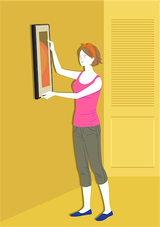 Woman hanging picture frame on wall Stock Photo - Premium Royalty-Free, Code: 6111-06837954