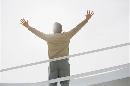 Sun shining behind businessman with arms raised Stock Photo - Premium Royalty-Free, Code: 6113-06497785