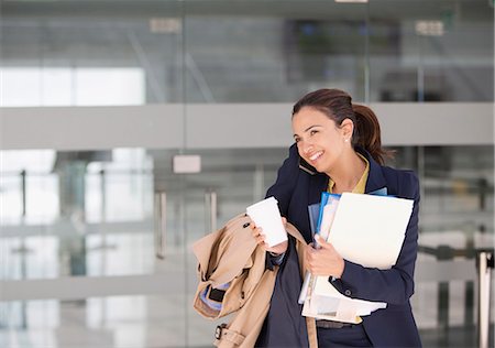 Smiling businesswoman multitasking on cell phone with coffee and paperwork Stock Photo - Premium Royalty-Free, Code: 6113-06497823