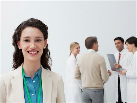 doctor meeting with business man - Portrait of smiling businesswoman with doctors in background Stock Photo - Premium Royalty-Free, Code: 6113-06497909