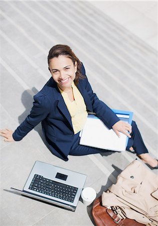 Portrait of smiling businesswoman with paperwork, coffee and laptop on steps Stock Photo - Premium Royalty-Free, Code: 6113-06497920