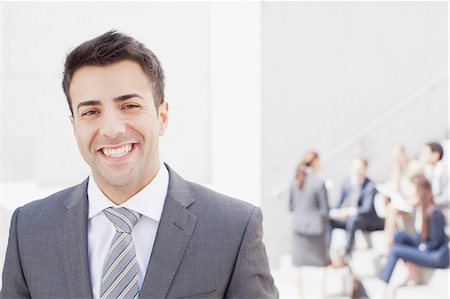 portrait businessmen outside - Portrait of smiling man with co-workers in background Stock Photo - Premium Royalty-Free, Code: 6113-06497926