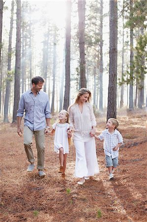 simsearch:630-06723838,k - Happy family holding hands and walking in sunny woods Photographie de stock - Premium Libres de Droits, Code: 6113-06498053