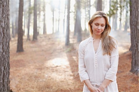 Portrait of serene woman in sunny woods Stock Photo - Premium Royalty-Free, Code: 6113-06498050