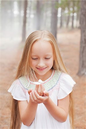 Close up of girl holding butterfly in woods Stock Photo - Premium Royalty-Free, Code: 6113-06498063