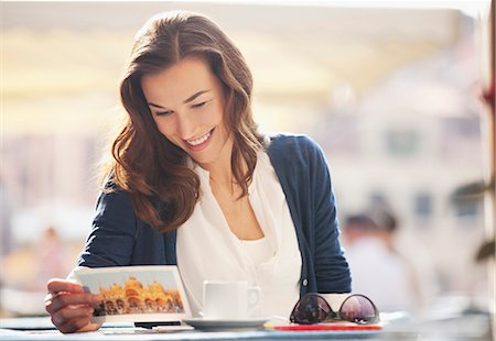 postcard shop - Smiling woman reading postcard at sidewalk cafe Photographie de stock - Premium Libres de Droits, Code: 6113-06498137