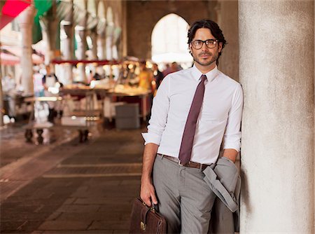 Portrait of confident businessman leaning against pillar at outdoor market Stock Photo - Premium Royalty-Free, Code: 6113-06498251
