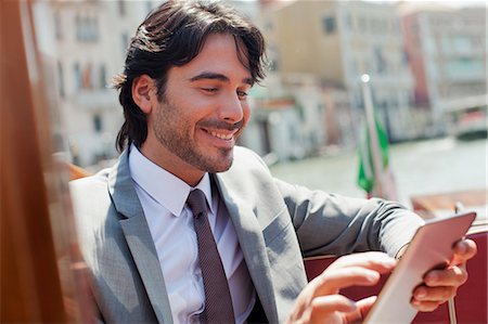 simsearch:6113-06498244,k - Smiling businessman using digital tablet on boat in Venice Foto de stock - Sin royalties Premium, Código: 6113-06498273