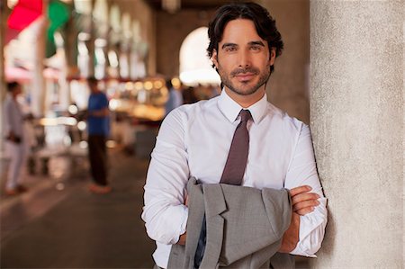 Portrait of smiling businessman leaning on pillar with arms crossed Stock Photo - Premium Royalty-Free, Code: 6113-06498203