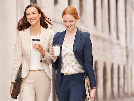 simsearch:6113-06899610,k - Smiling businesswomen walking with coffee Stock Photo - Premium Royalty-Free, Code: 6113-06498239