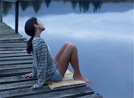 Serene woman sitting on dock over lake Stock Photo - Premium Royalty-Free, Code: 6113-06498463