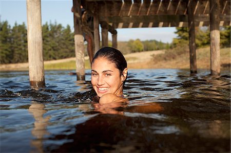 simsearch:6113-06498552,k - Portrait of smiling woman swimming in lake under dock Stock Photo - Premium Royalty-Free, Code: 6113-06498489