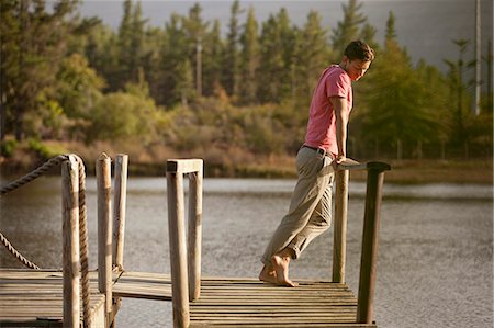 Serene man standing at railing of dock over lake Stock Photo - Premium Royalty-Free, Code: 6113-06498494