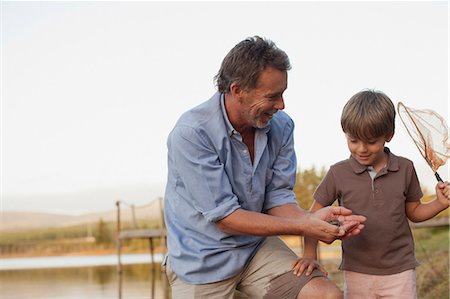 simsearch:6113-07906393,k - Smiling grandfather and grandson fishing at lakeside Stock Photo - Premium Royalty-Free, Code: 6113-06498499