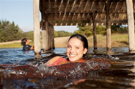 simsearch:6113-06498552,k - Portrait of smiling woman swimming in lake under dock Stock Photo - Premium Royalty-Free, Code: 6113-06498542