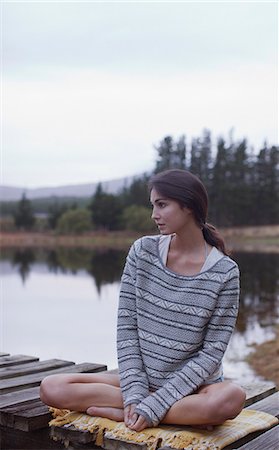 Pensive woman sitting on dock at lake Stock Photo - Premium Royalty-Free, Code: 6113-06498502