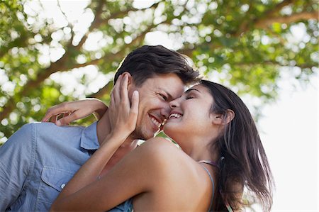 Smiling couple hugging under tree Stock Photo - Premium Royalty-Free, Code: 6113-06498534