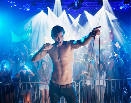 Bare chested singer performing with crowd in background Foto de stock - Sin royalties Premium, Código: 6113-06498676