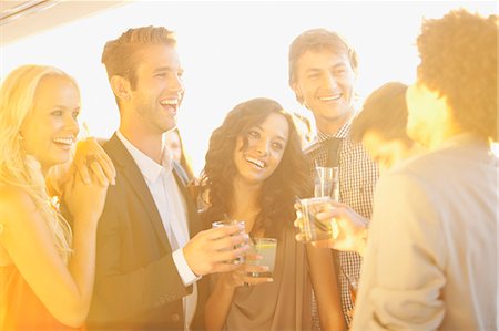 socializing - Smiling friends drinking cocktails on sunny balcony Foto de stock - Sin royalties Premium, Código: 6113-06498698