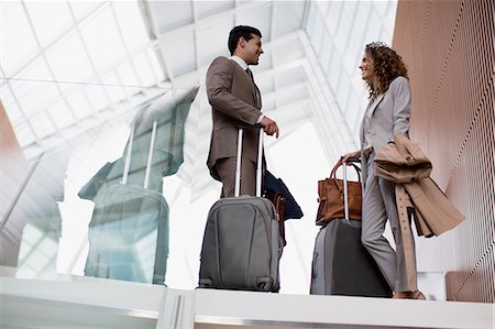 pictures of two people talking at the airport - Smiling businessman and businesswoman with suitcases talking in airport Stock Photo - Premium Royalty-Free, Code: 6113-06498751