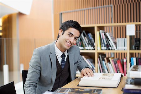 study book - Portrait of smiling businessman reading book in library Stock Photo - Premium Royalty-Free, Code: 6113-06498760