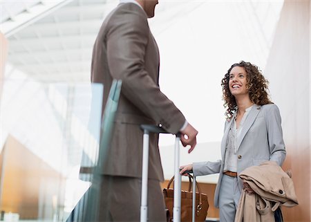 suitcase travel - Smiling businesswoman talking to businessman in airport Stock Photo - Premium Royalty-Free, Code: 6113-06498771