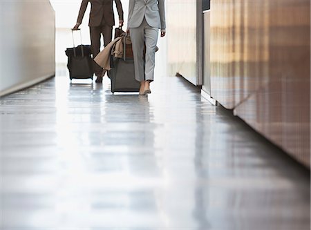 Businessman and businesswoman pulling suitcase down ramp in airport Foto de stock - Sin royalties Premium, Código: 6113-06498787