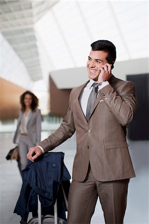 Smiling businessman talking on cell phone at airport Stock Photo - Premium Royalty-Free, Code: 6113-06498795